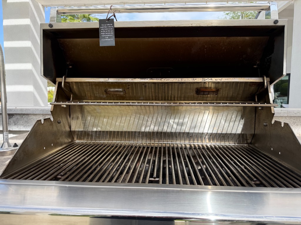 Stainless grill interior with clean grates, warming rack, and hood after professional deep cleaning