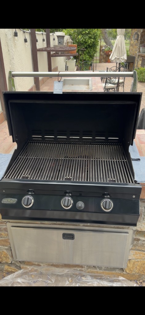 Built-in stainless outdoor grill professionally cleaned with hood open